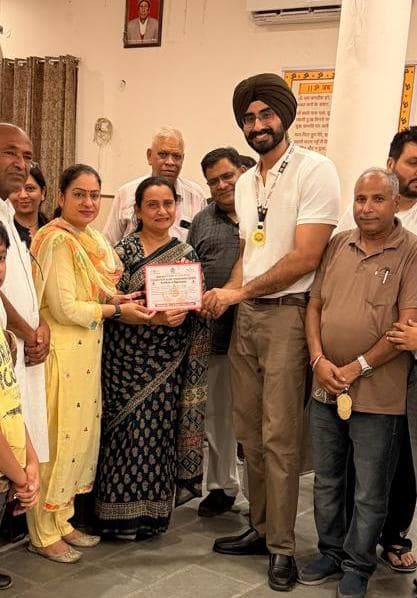 Dr. Ravitej Singh Bal being presented with a certificate of appreciation by organisers at a community event
