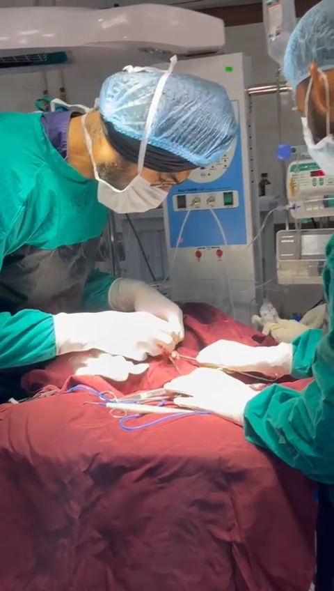 Dr. Ravitej Singh Bal and a colleague operating in a fully draped theatre
